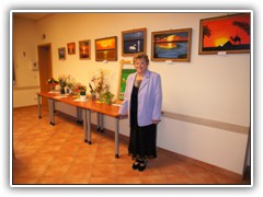 Hier steht Frau Mender vor einem Teil ihrer gemalten Bilder.